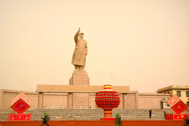 mao statue in background. red lanterns in foreground. 