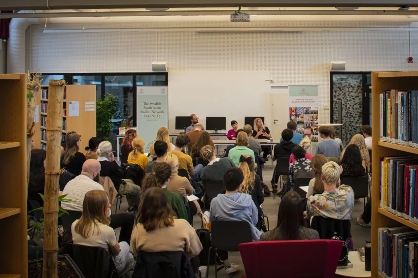 photo from event, three speakers up front with audience 